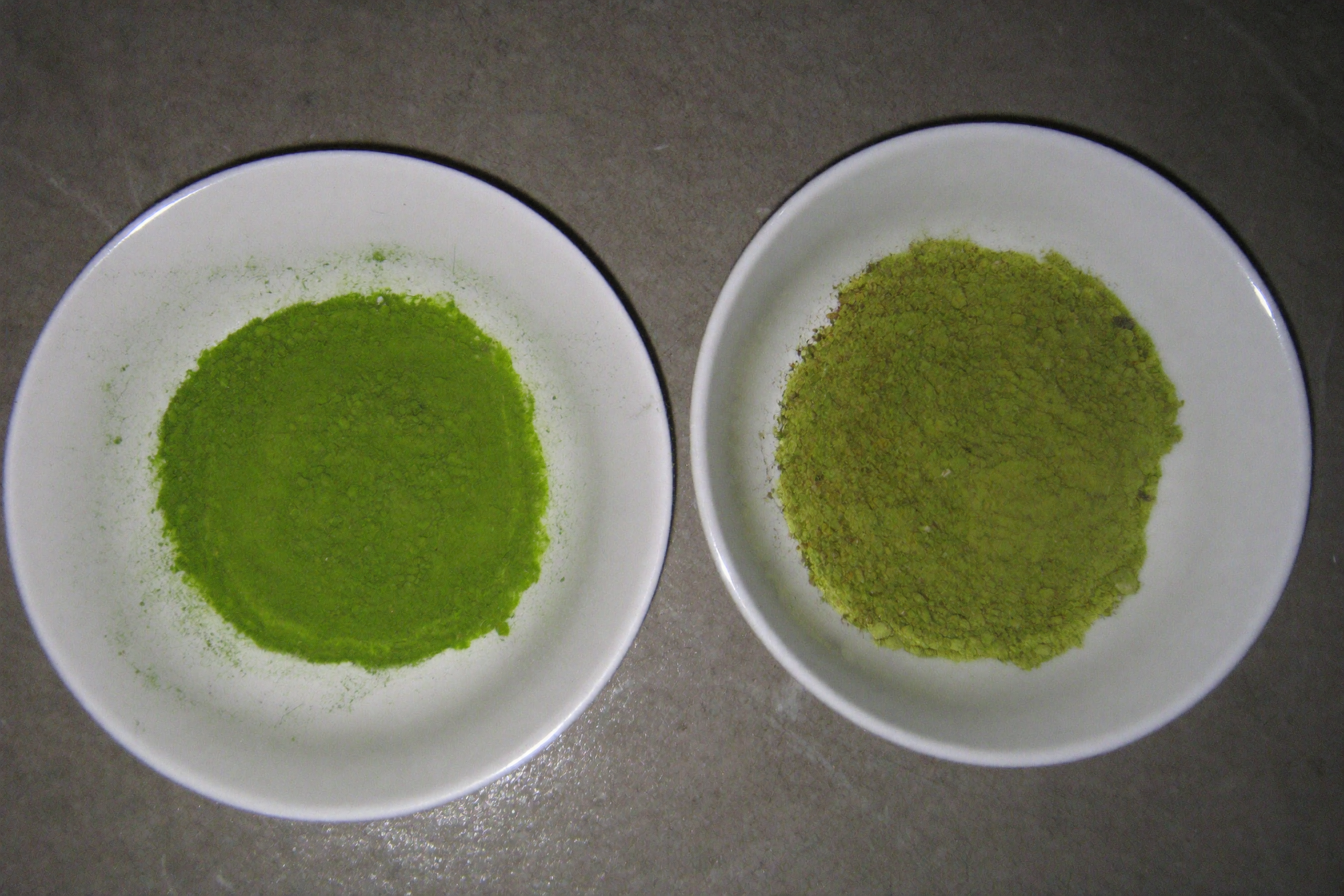 Vivid jade matcha powder next to dull olive matcha powder in two dishes