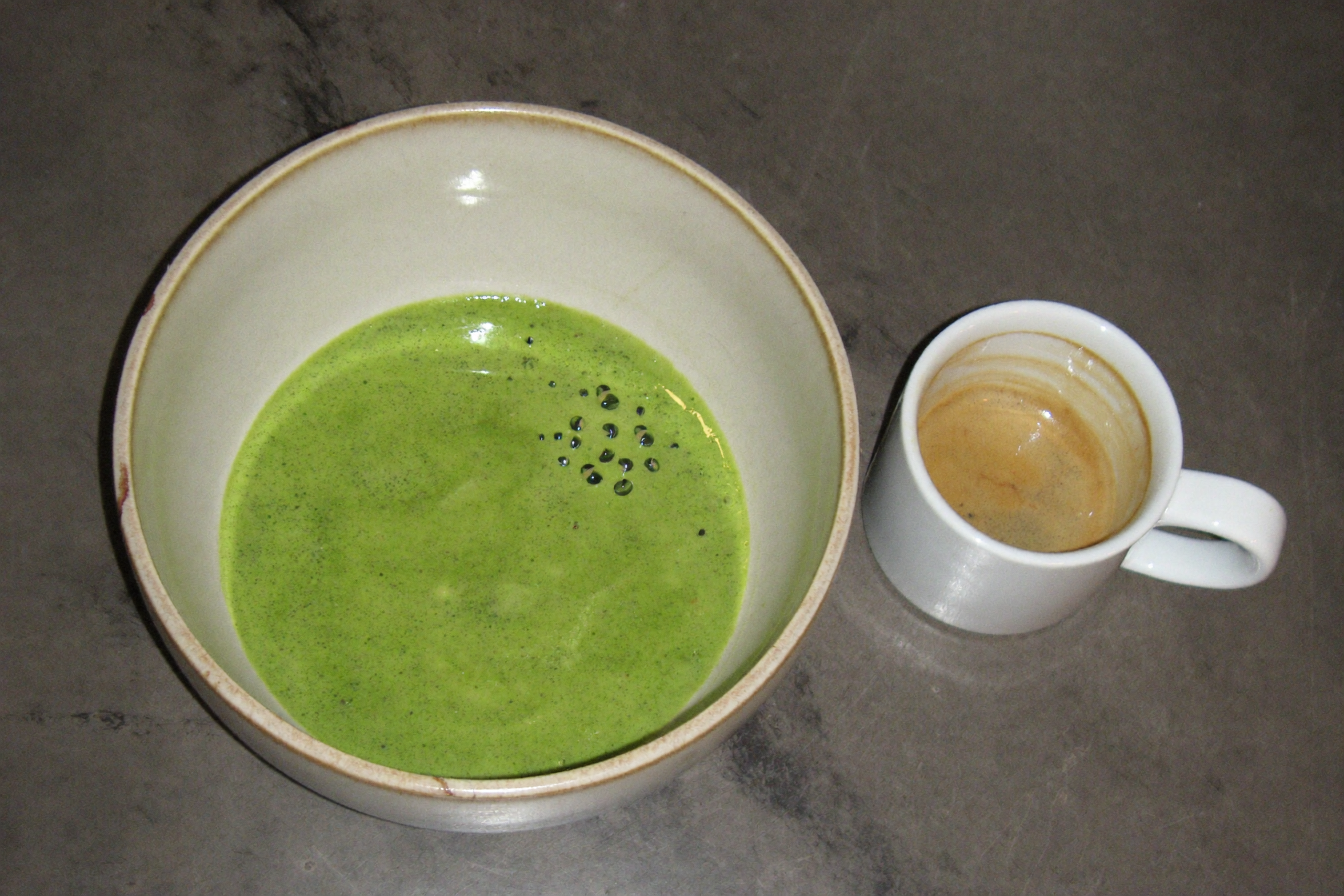 Bowl of whisked matcha next to an espresso cup for a caffeine comparison