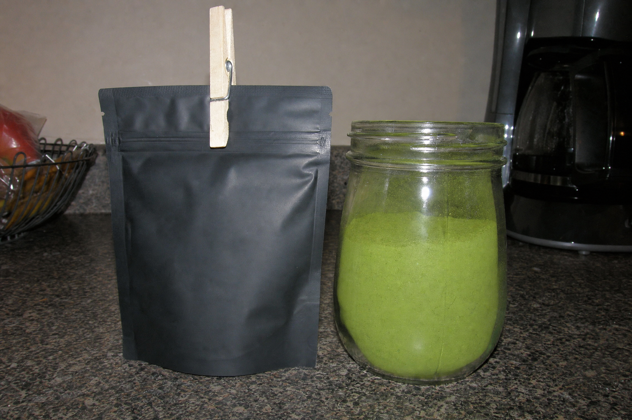 Resealable black matcha pouch with a clip and an airtight glass jar of matcha powder